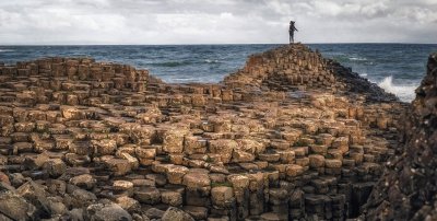 Giants Causeway Day Tour from Dublin Person on giants causeway rocks while waves crash against shore